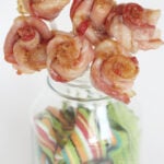 Sweet bacon roses on skewers displayed in a mason jar.