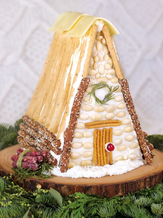 Charcuterie Chalet is a holiday decoration of an A-framed house structure with breadsticks, cheese, and various food items.
